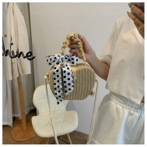 Detail view of straw woven apple bag with polka dot scarf handle and rope shoulder strap