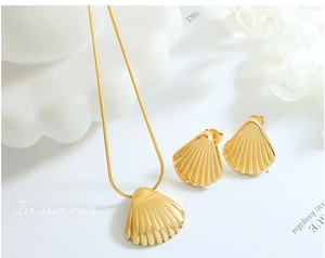 Close-up of golden shell pendant necklace and matching earrings on white floral background