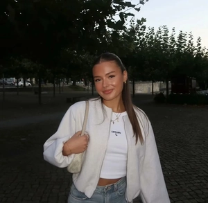 Photo en extérieur d'un blouson aviateur blanc porté avec un jean clair et un t-shirt
