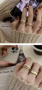 Close-up of a double-layered gold ring set featuring smooth and textured finishes on a finger