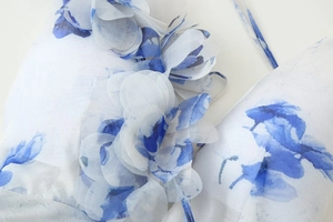 Détail de l'applique fleurie 3D et du motif floral bleu sur le tissu de la robe col V