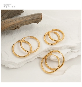 Detailed comparison of three different sized gold hoop earrings on a stone base