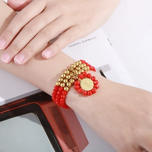 Detail of multi-layer red beaded bracelet with Saint Benedict medal on model wrist