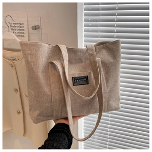 Close-up of textured beige canvas tote bag showing weave detail and black logo label