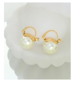 Gros plan de boucles d'oreilles perles dorées à l'or 18 carats sur support blanc