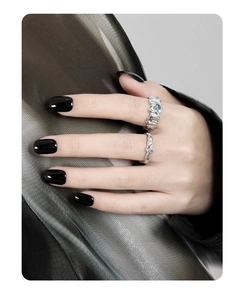 Detailed view of silver rings with blue zircon and irregular texture on model hand