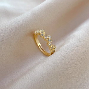 Macro shot of gold leaf zircon ring showing marquise-cut stones on beige silk cloth