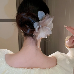 Détail d'un pic à cheveux fleur en tissu rose avec glands de perles sur un chignon
