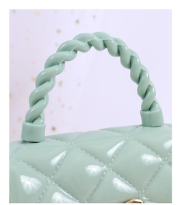 Detail of light green jelly bag featuring quilted pattern and woven style plastic handle