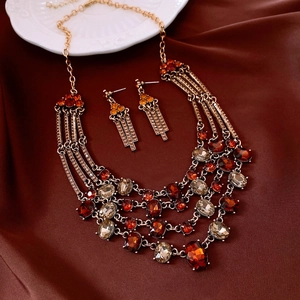 Macro shot of vintage style triangle jewelry set with red and champagne crystals on silk