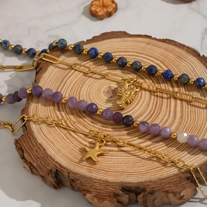 Detail of natural stone bracelets with starfish and lobster charms on a wood slice