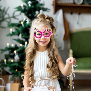 Child wearing festive pink Christmas glasses with snowman and Santa decor in holiday setting