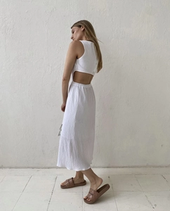 Detail of white textured fabric sleeveless dress featuring back button and waist cutout