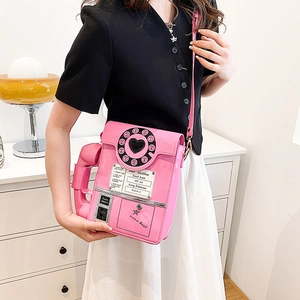 Pink telephone-shaped crossbody bag in shiny faux leather styled on a female model