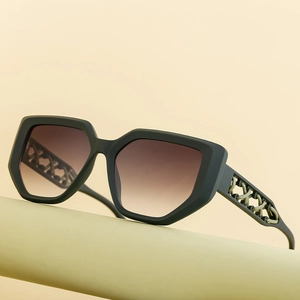 Cat eye sunglasses with olive green frames and metal woven chain temples on a display pedestal