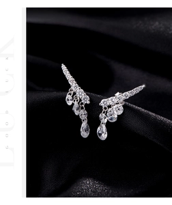Macro detail of silver drop earrings with pear-cut zirconia on black silk fabric
