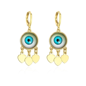 Detail von vergoldeten Evil Eye Ohrringen mit herzförmigen Anhängern auf weißem Hintergrund