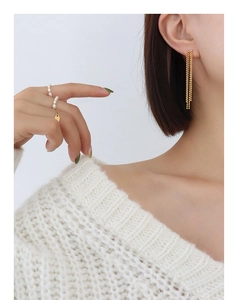 Gros plan de boucles d'oreilles à franges dorées et d'une bague en perles blanches
