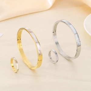 Detailed view of stainless steel jewelry set with white shell inlay on silk fabric