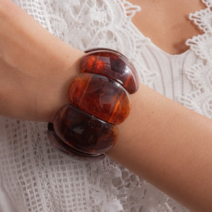 Detailed view of a chunky amber acrylic bracelet with elegant marbled patterns on a wrist