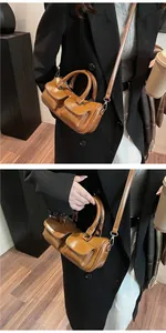 Detailed view of camel saddle bag featuring dual front pockets and glossy leather finish