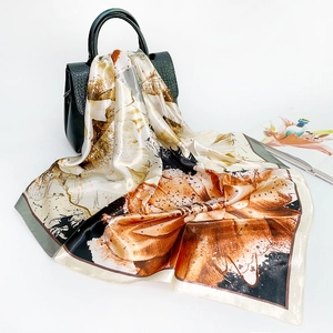 Floral satin square scarf in brown and beige draped over a black handbag