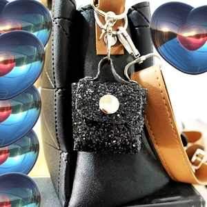 Close-up of a black sequin mini pouch keychain hanging on a quilted leather handbag