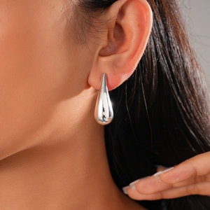 Close-up of a silver acrylic water drop earring worn by a model in a minimalist style