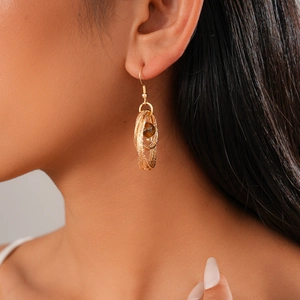Detail of layered gold geometric earrings with brown tiger eye stone on model