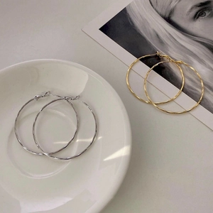 Macro shot of large textured gold and silver hoop earrings on a magazine and plate