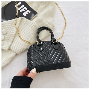 Detail of black shell-shaped jelly bag showing glossy PVC texture and gold chain strap