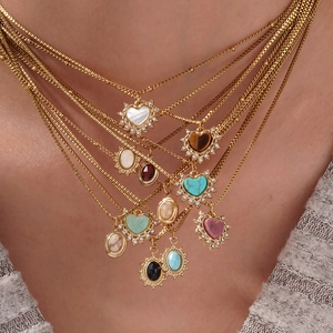 Minimalistische Goldkette mit herzförmigen Natursteinen am Hals des weiblichen Modells
