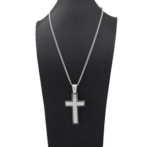 Close-up of iced-out cross pendant with black oil drip on silver cuban link chain