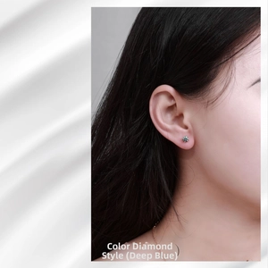 Detailed close-up of dark blue moissanite stud earring worn on model's ear