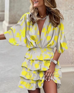 Detail of V-neck ruffled dress featuring vibrant yellow floral print and tiered hemline