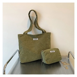 Olive green corduroy tote bag and small chain pouch set on a metal display stand