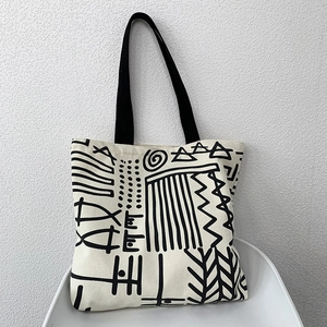 Macro detail of canvas tote bag with black geometric pattern on a white chair