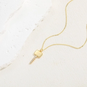 Macro detail of gold key pendant necklace featuring sparkling cubic zirconia stones