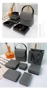 Detail of dark gray jewelry packaging set including gift boxes and matching paper bags