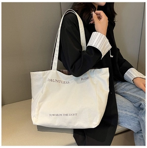 Detail of white canvas tote bag with black Dauntless text and stylish interior check pattern