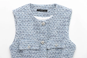 Detailed macro view of the blue and white tweed vest fabric with silver floral buttons