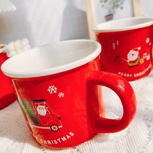 Close-up of red Christmas ceramic mug with Santa Claus truck and snowflake patterns