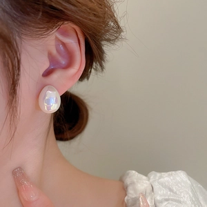 Gros plan d'une boucle d'oreille goutte en perle nacrée portée sur l'oreille