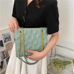 Detail of mint green quilted crossbody bag with gold chain strap and padded leather shoulder