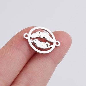 Makroaufnahme eines Lippen-Anhängers aus Edelstahl zwischen den Fingern gehalten