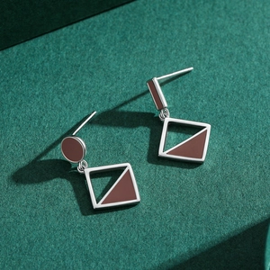 S925 sterling silver asymmetrical earrings with brown enamel on a textured background