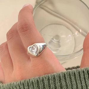 Detail of 925 sterling silver heart signet ring worn on index finger with clear zircon