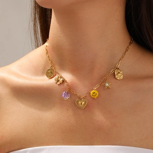 Détail de collier doré avec pendentifs cœur, smiley et cristal violet sur une chaîne chic