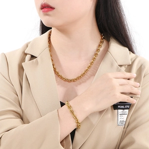 Close-up of a gold stainless steel O-chain necklace and bracelet set on a fashion model