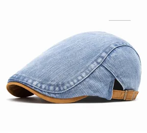 Detail of blue denim beret with brown brim, metal buckle, and contrast stitching